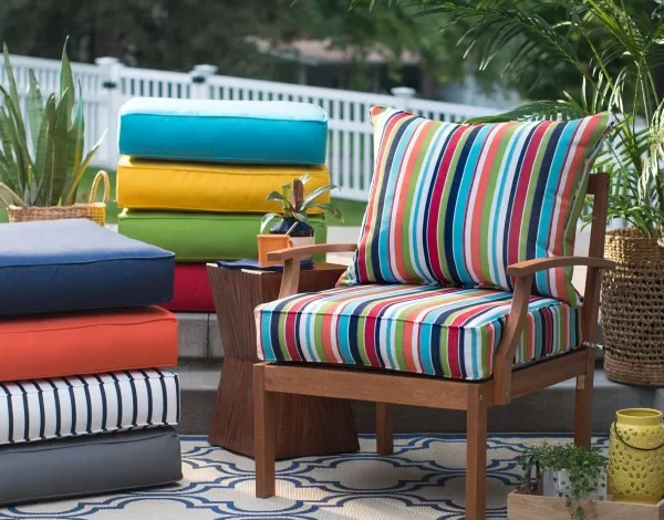 A vibrant outdoor patio setting featuring a wooden chair with colorful striped fabric cushions.